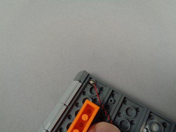 As shown in the second photo for this step, mount the second green roof light at the top left corner of the left roof section.