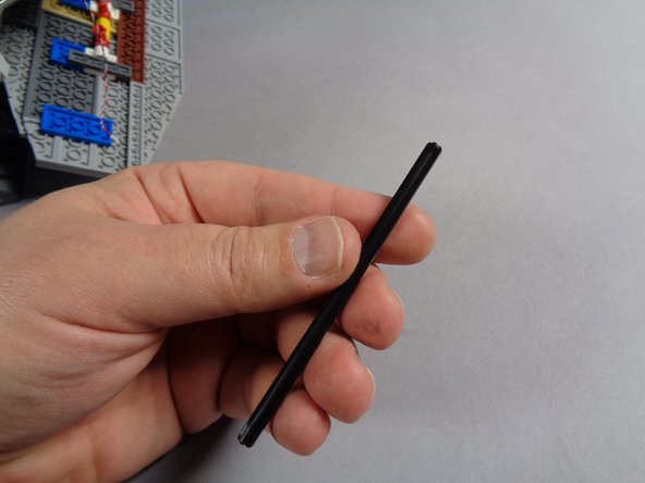 Remove the long black Technic axle from the Core Parts bag as shown in the first photo.