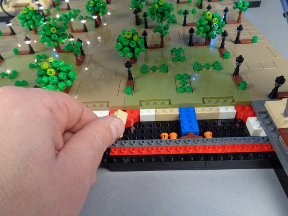 As shown in the photos for this step, remove the 2x3 tan brick under Panel 3R and run the control cable between the studs on the black bottom plate, then re-attach the tan brick on top of the cable.