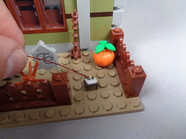 As shown in the third photo, replace the fencing section and run the LED Light wire behind the fences toward the left.