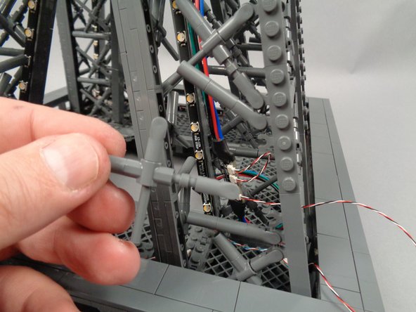 As shown in the photo for this step, remove the "X" crossbar on the outside of the first pillar to make room to connect the control cable.