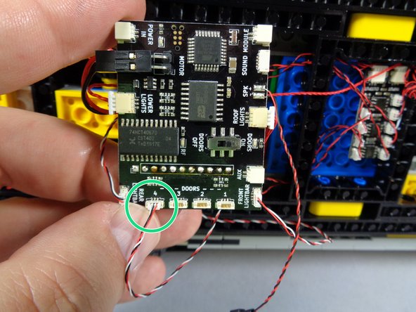 As shown by the green circle in the photo for this step, connect the door switch wire to one of the four DOORS plugs on the main controller.