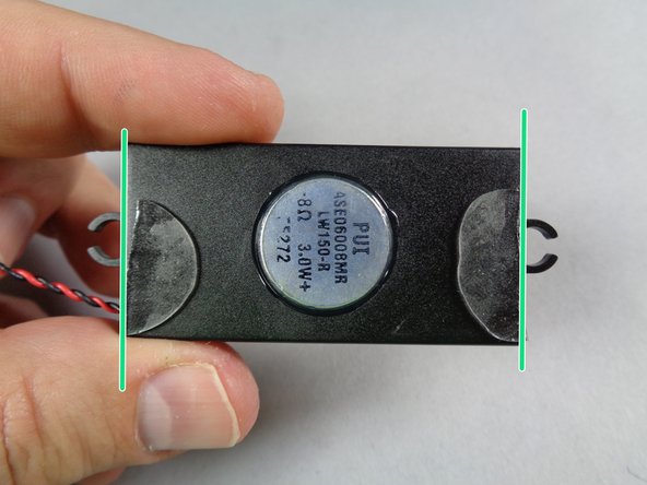 As shown in the second photo for this step, attach the two halves of the glue disc to the  bottom edges of the speaker.  As shown by the two green lines, align the flat edges of the cut disc pieces with the flat edges of the speaker.  The disc pieces should not stick out beyond the edge of the speaker.