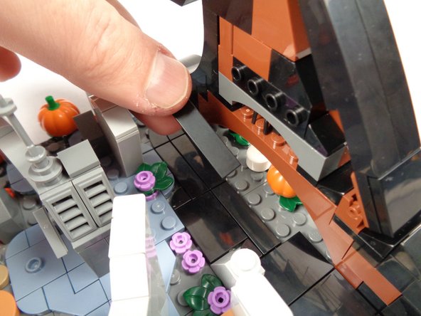 As shown by the orange arrow in the third photo for this step, re-attach one of the two tiles you removed into the center of the opening, leaving two studs open on either side.