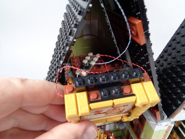 As shown in the photos for this step, re-attach the explorer painting, being careful not to pinch or pull any wires in the Technic pins as you snap the frame back into place.