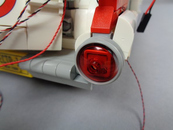 As shown in the first and second photos for this step, press the transparent red dish back into place.