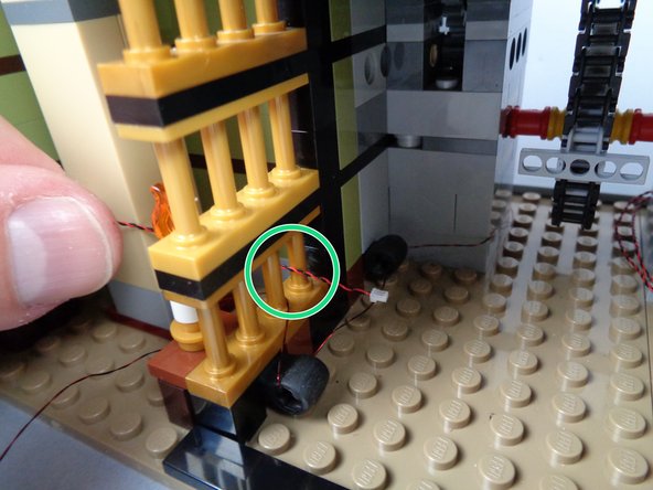 As shown by the green circle in the first photo, pass the plug for the second candle through the gap in the gold bars.