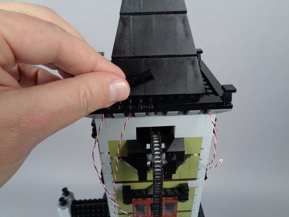 As shown in the photos for this step, replace the large black plate and large black tile you removed earlier onto the top of the roof.