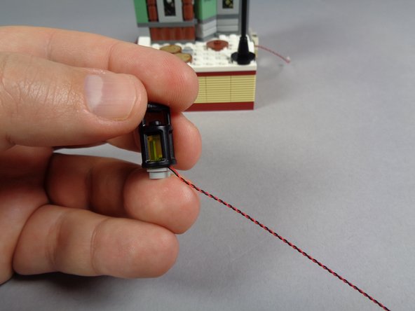 As shown by the yellow arrows in the second photo, carefully bend the LED light wire around the side of the stud with your fingernail.