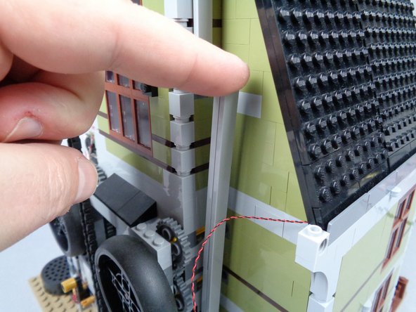 As shown in the first and second photos for this step, route the jewel case light wire behind the plates and tiles running up the back of the elevator shaft.