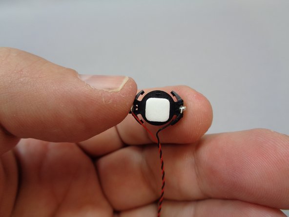 As shown in the second photo, attach a sticky square to the bottom side of the battery holder.