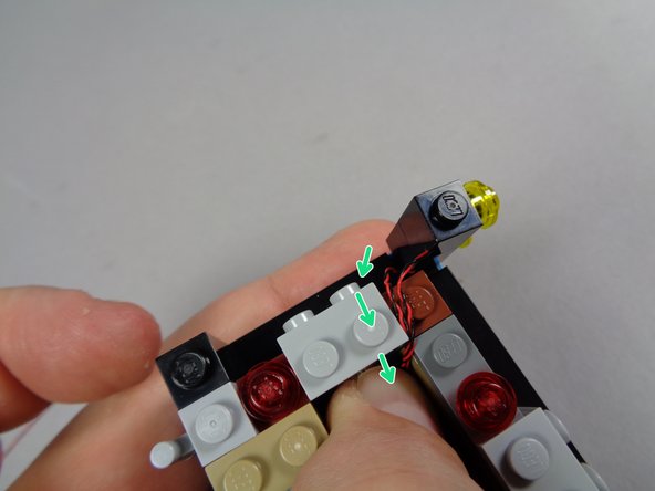 As shown by the green arrows in the first photo for this step, position the brick stack with wires coming out the right side on the left side of the marquee base.