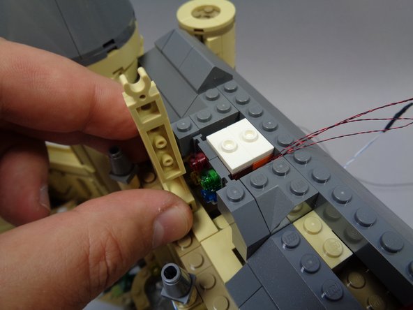 As shown in the photos for this step, carefully mount the pre-lit stained glass window and replace the parts in front of and behind it.