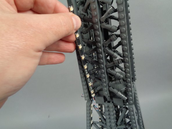 As shown in the photos for this step, attach the top of strip #2 to the tower frame, and re-position brace elements as needed to make room for the LED lights and strip.