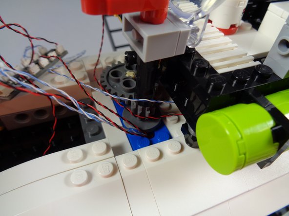 As shown in the second photo for this step, you should have two wires extending down from the roof: the red 3-wire control cable and the thicker red/black motor wire.  Pull both wires so they come out the back of the Ecto-1.