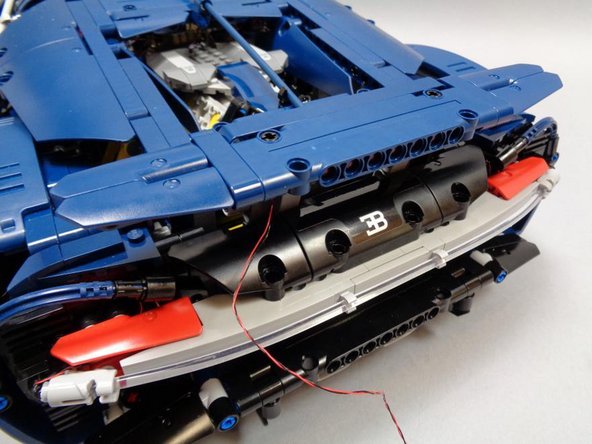 Re-attach the spoiler to the car, and carefully run the LED cable down the left side and loop the wires through the holes in the interior Technic beam as shown.