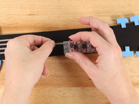 Lift up the first button and use a small piece of Maker Tape to start a path out to the left of the button. 