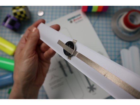 Follow the instructions on the template to add a small loop of maker tape to the Negative side of the battery, then place it on top of the piece that was wrapped over the edge.
