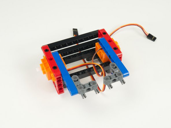 Add the two gray 90 degree connectors to the blue rear stabilizer beams as shown so the pins are facing towards the rear of the rover.