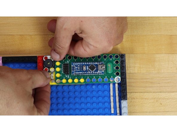 Press down the Piezo Speaker onto LEGO bricks over Maker Tape.