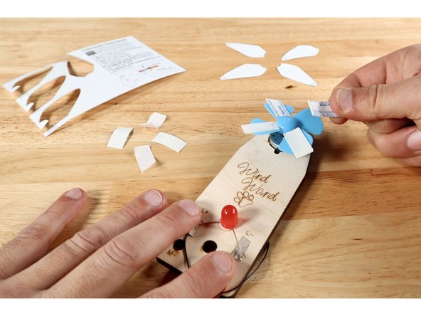 After cutting each of the blades from the template card, peel one side of the foam tape pieces. Stick the foam tape pieces to each of the blue plastic fan blades.