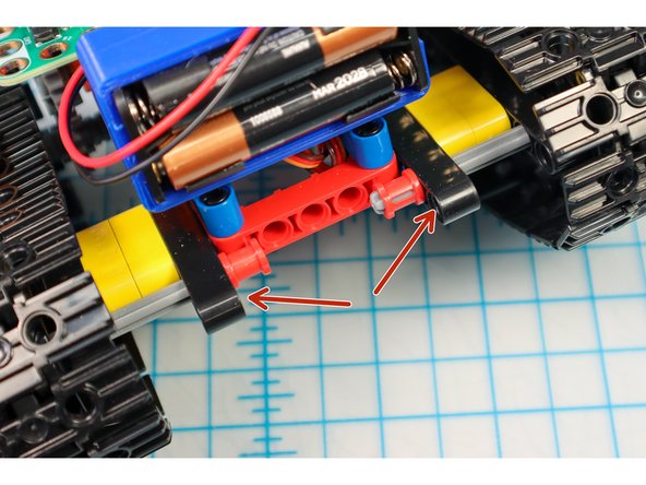 Use two pin/beam sets to connect the paper to the back of the tank under the battery pack where shown.