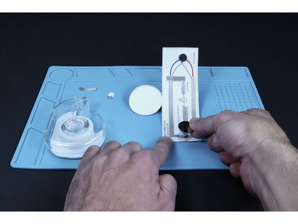 Press the battery atop that tape loop so that the positive (+) side faces UP.