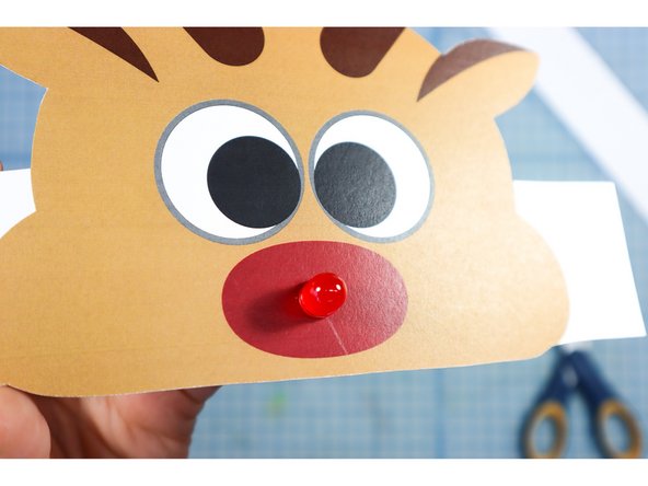 Poke small holes in the center of the nose where shown and insert the LED, matching the positive and negative notation.