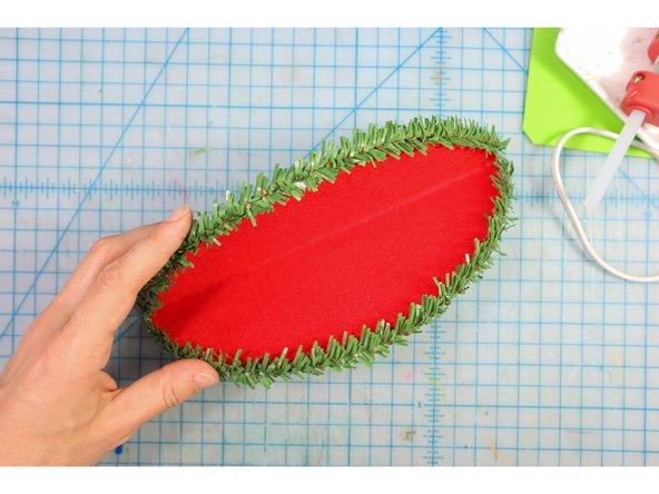 Glue evergreen pipe cleaners or green garland to the edges of the lips as shown.