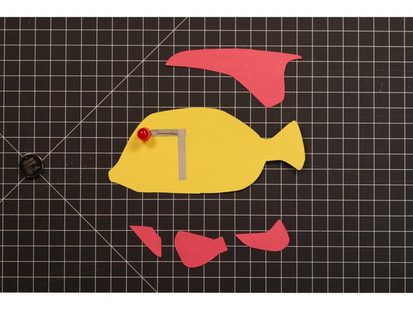 Tape down the negative LED leg (which is on the front side of the fish) using Maker Tape.