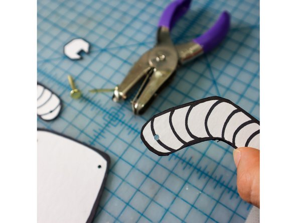 Use a hole punch to put a small hole in the arm and the body. If you have one, use an 1/8 inch hole punch.