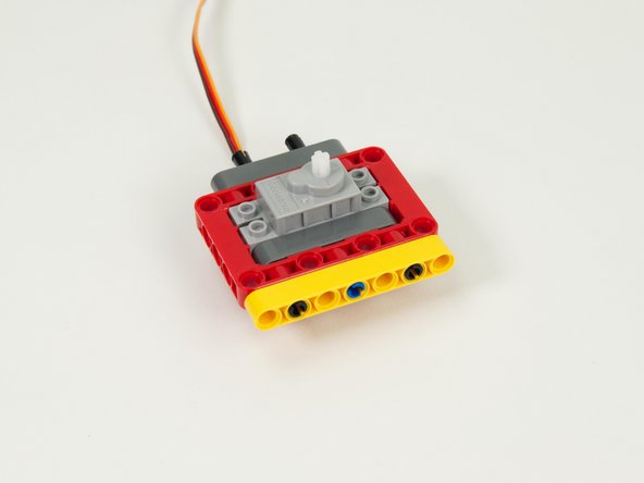 Add a yellow 7 beam to the pins on the front of the assembly.