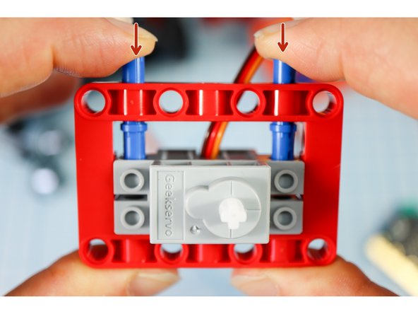 Position the servo motor inside the frame so that the holes align with the blue long pins.
