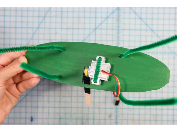 Add pipe cleaners through the remaining holes as shown. These will be used like giant &quot;twist ties&quot; to tie the backplate to the trunk of the tree.