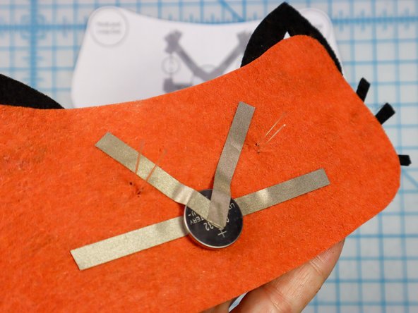 Fold each LED leg down flat against the felt, making sure the longer, positive legs touch the &quot;V&quot; and the shorter, negative legs touch the horizontal piece.