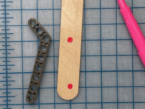 Make two holes in the popsicle stick and secure it to the lego piece with zip ties.