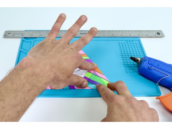 Use a hot glue gun to place hot glue on the inside of a frame while pressing one of the colored triangles into place on top. Be sure to be accurate with your placement as each edge of a given face will eventually need to be fastened to the next. Overhang can make this tricky.  Do this ONE FACE AT A TIME. 