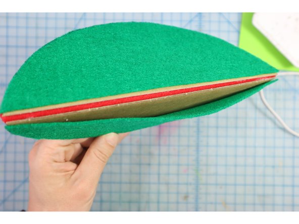 Glue the green felt pieces to the other side of the cardboard. One of the green pieces should be glued down completely. The other should only be glued around the round edge, creating a &quot;pocket&quot; to insert the popsicle stick into later.