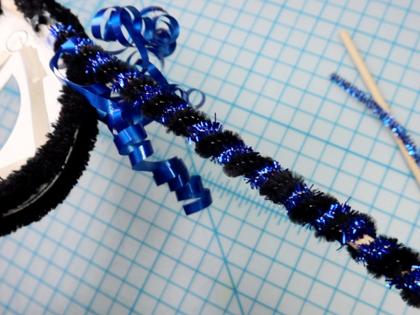 Wrap pipe cleaners around a wooden dowel, then glue the dowel to the back for a masquerade style handheld mask.