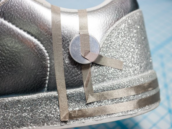 Stick the piece of Maker Tape connected to the sensor to the top of the battery as shown, making sure it doesn't touch the other piece.