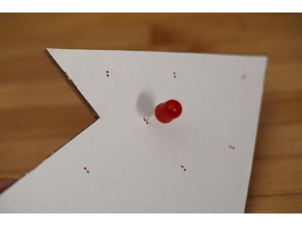 Put the legs of the LEDs through the holes with the longer leg (positive) towards the center of the arrow and the shorter leg (negative) towards the outside of the arrow.