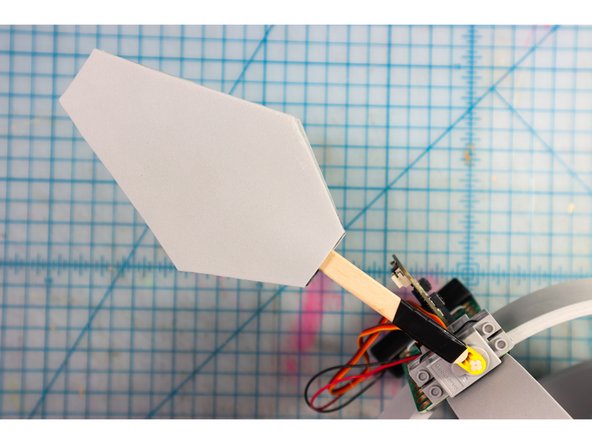Press the two pieces together, then slide the popsicle stick between them. By keeping the glue away from the stick, you can insert it more or less to match the height of your Santa Hat.