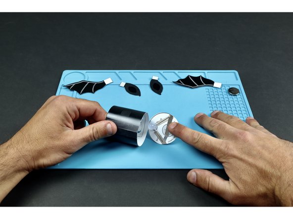 First, use two Maker Tape sections to secure LED legs in place. Make sure to note the length of the legs and orient the LED/legs to match the diagram. Then, add the Maker Tape section shown so that it connects to the tape path leading from the SHORT LED leg.