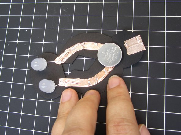 Place a battery so that bottom (Negative) side is over the two Negative lines of tape.  (Top side)