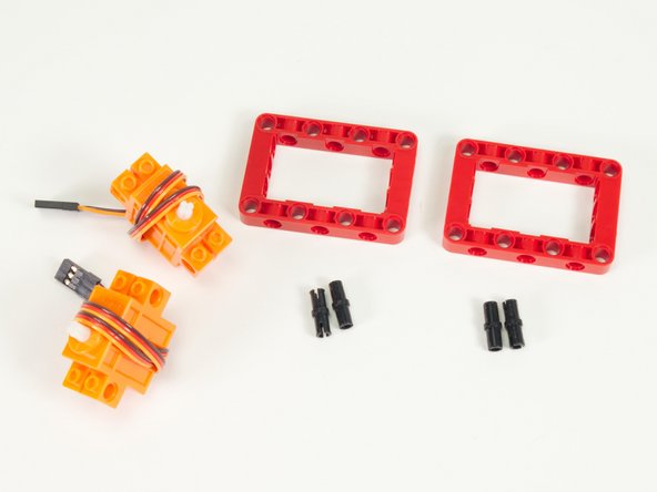 We'll start by attaching the servos to the red frame pieces using pins.