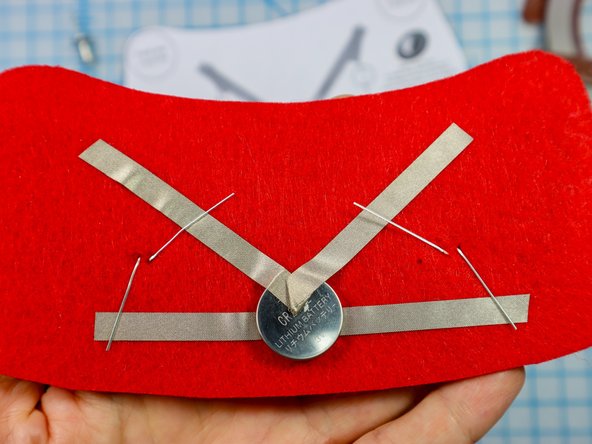 Fold each LED leg down flat against the felt, making sure the longer, positive legs touch the &quot;V&quot; and the shorter, negative legs touch the horizontal piece.