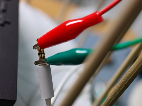 An AUX Cable will typically have two or more connections separated by little black rings. Connect the GND alligator clip to the ring closest to the cable and the other alligator clip to the tip as shown.