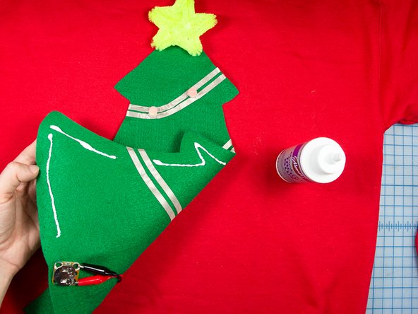 Use tacky glue to glue the tree to the center of the sweatshirt. Leave a gap in the glue around the battery pack.
