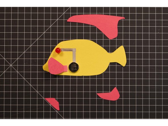 We won’t add our battery yet, but you can put it in place so we know where the pectoral fin needs to go. The fin will connect the circuit and also be used as the battery cover.