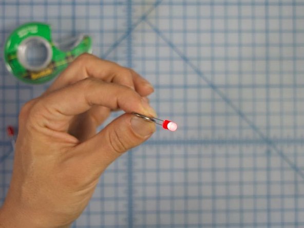 Place the battery between the legs of the LED, aligning the positive (longer) leg with the positive side of the battery and the negative (shorter) leg with the negative side.